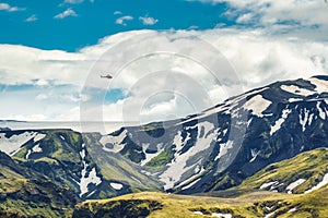 Landscape of lush rugged volcanic mountain with helicopter flying in Icelandic highlands on summer at Thorsmork