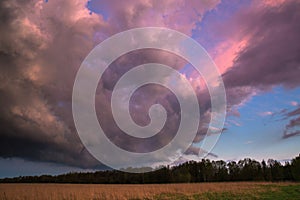 Landscape with majestic colorful dramatic red sky with fluffy clouds at sunset before before a thunderstorm and rain