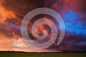 Landscape with majestic colorful dramatic red sky with fluffy clouds at sunset before before a thunderstorm and rain