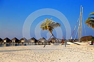 Landscape on Maldives island, luxury water villas resort and wooden pier. Beautiful sky and ocean and beach with palms background