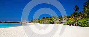 Landscape on Maldives island, luxury water villas resort and wooden pier. Beautiful sky and ocean and beach with palms background