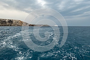 Landscape of Maltese island Comino Kemmuna with water waves in slight motion blur effect and the ferry in the background