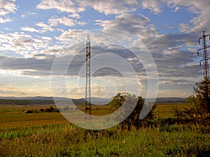 Landscape with meadows, fields, electric pylons, transmitters and high hills in the distance