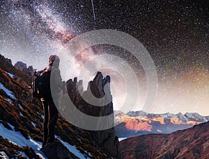 Landscape with milky way, Night sky stars and silhouette of a standing photographer man on the mountain.