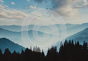 Landscape of misty mountains. View of coniferous forest, layers of mountain and haze in the hills at distance. Beautiful cloudy sk photo