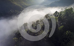 Landscape misty panorama. Fantastic dreamy sunrise on rocky mountains with view into misty valley below. Foggy clouds above