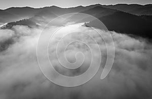 Landscape misty panorama. Fantastic dreamy sunrise on rocky mountains with view into misty valley below. Foggy clouds above