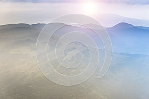 Landscape of mountain range with visible silhouettes through the morning colorful fog. Sunrise in the mountains.