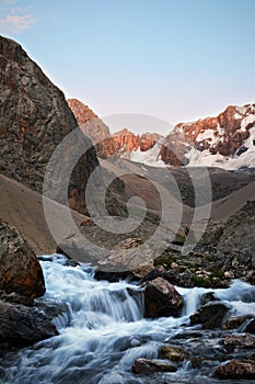 Landscape of mountain river with small waterfall over rocks