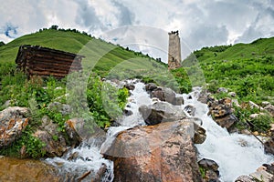 Landscape of a mountain stream in the village of Adishi, Svaneti, Georgia with a Svan ancient tower on a hill
