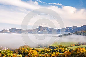 A landscape with mountain surrounded by fog in the autumn season