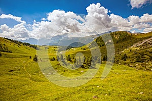 landscape with mountains, hills, clouds, meadow and trees