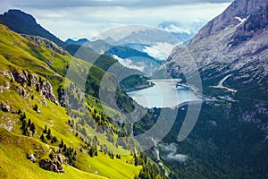 landscape with mountains, hills, Fedaia lake, clouds and rocks