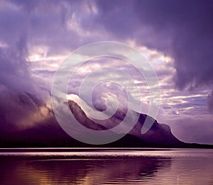 Landscape. Mountains and lake in mist in morning with purple color