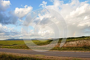 Landscape of mountains, path and plains with clouds