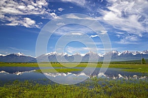 Landscape with mountains reflecting in the water on summer day. Buryatia, Tunkinskaya valley