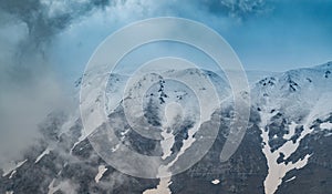 Landscape with the mountains in snow and heavy clouds in the background