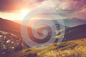 Landscape in the mountains:snowy tops and spring valleys at sunlight.