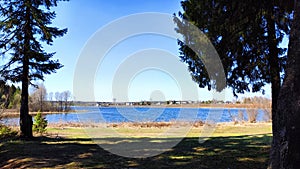 Landscape and nature with calm water of big lake, trees on the shore and blue sky on autumn or spring sunny day. Sun and