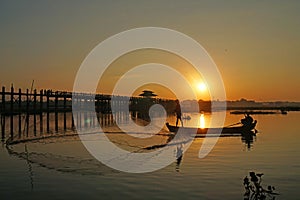 Landscape - nature scene of Silhouette  longest wooden bridge and traditional boat on the lake at u bein bridge with sunrise. This