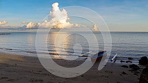 Landscape nature sunrise scenery of seacoast,fishing boat & clouds at Batu Manikar beach,Labuan,Malaysia.