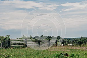 Landscape with old broken wooden fence on dry pasture