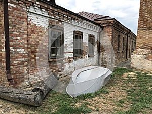 Landscape with old iron gray overturned boat old logs and brick abandoned factory of the 19th century.Mobile photo in natural dayl