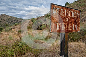 landscape of old train line deactivated with rusted sign with warning, atencion al tren.  la fregenera, spain. photo