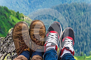 Landscape, travel, tourism. A pair of feet in the shoes against the background of the mountains. Horizontal frame