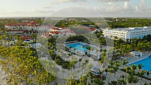 Landscape with palm trees, hotels, pool, white sand, azure sea