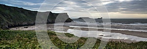 Landscape panorama Rhosilli Bay beach at sunset with moody sky