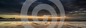 Landscape panorama Rhosilli Bay beach at sunset with moody sky