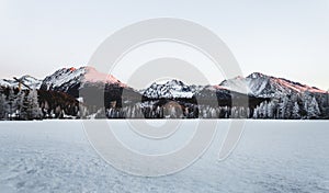 Fotografie krajiny zamrzlého a zasněženého Štrbského plesa Štrbské pleso v zimním období. Hory na Slovensku se zamrzlým jezerem na