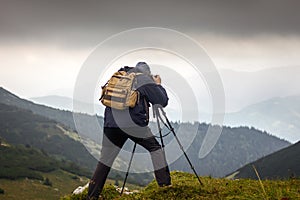 Landscape photographer with tripod in mountains