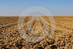 Landscape with plowed field with focus on foreground and horizon over land