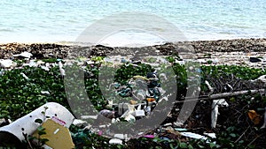 Landscape of polluted beach full of litter and sea on the background