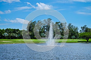 Landscape pond with a fountain and wide green lawns