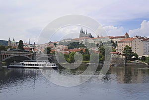 Landscape of Prague, Czech Republic on a sunny day. In the foreground is a boat on the Vltava river .