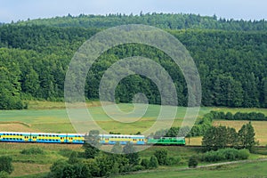 Landscape with a railway line, train, hills and fo