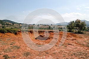 Landscape with red dry cracked soil between hills and mountains in Xieng Khouang Province, Laos