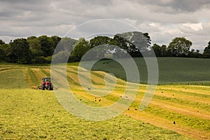 Landscape with red tractor mowing on hilly Irish farm