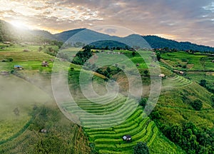 Landscape of rice terrace and hut with mountain range background and beautiful sunrise sky. Nature landscape. Green rice farm.