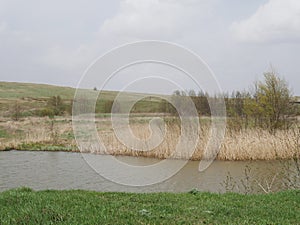 Landscape with a river and a field. Green grass. In the summer. Dull