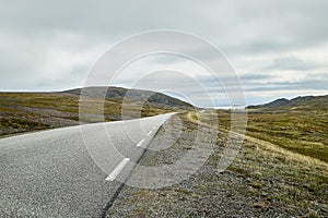 Landscape with road in tundra in Norway at cloudy evening