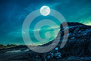 Landscape of rock against sky and full moon above wilderness are