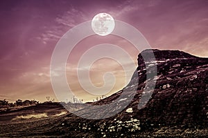 Landscape of rock against sky and full moon above wilderness are