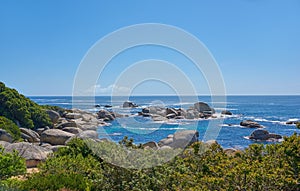 Landscape of rocks in the ocean on a hot summer day in Hout Bay, Cape Town. Calm waves splashing against rocky and