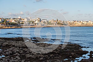 Landscape of a rocky coast overlooking the sea and the city at sunset in Estoril, Portugal