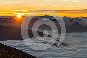 Landscape of rocky hill silhouettes covered in the fog under the sunlight during a beautiful sunset