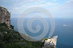 Landscape with rocky mountains with dense vegetation and calm sea far and down on horizon line on sunny day